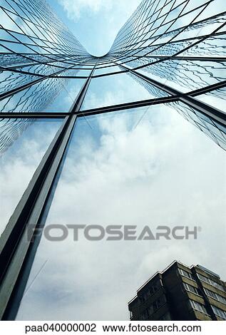 Stock Image - Building reflected in skyscraper's facade, low angle view. Fotosearch