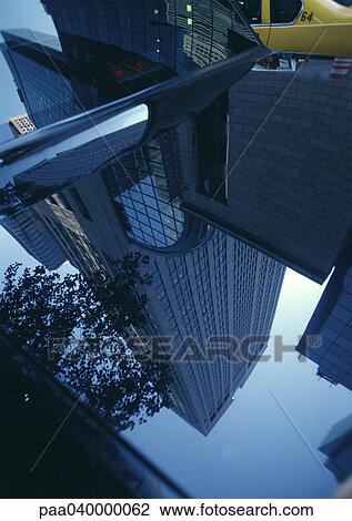 Stock Image - Skyscraper reflected in hood of car. Fotosearch