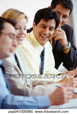 Business people sitting side by side at a table, smiling View Large Photo Image Stock Photography - Business people sitting side by side at a table, smiling. Fotosearch