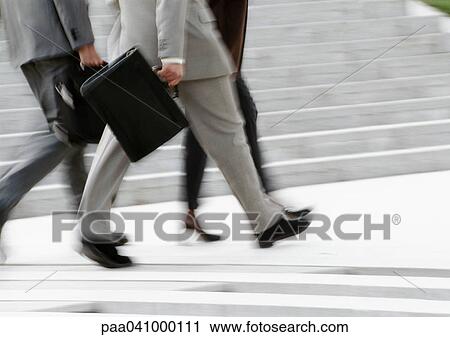 Stock Image - Business people walking, low section, blurred, b&w. Fotosearch