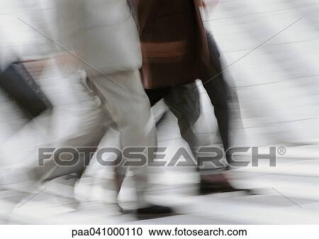 Stock Image - Business people walking on pedestrian crossings, low section, blurred, b&w. Fotosearch