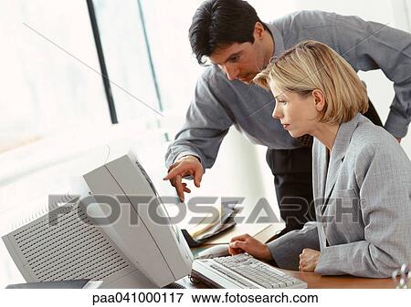 Businessman and businesswoman looking at computer screen View Large Photo Image Stock Photo - Businessman and businesswoman looking at computer screen. Fotosearch