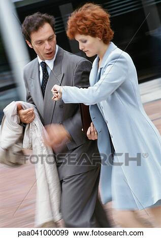 Businessman and businesswoman walking side by side outside, businesswoman looking at watch View Large Photo Image Stock Photo - Businessman and businesswoman walking side by side outside, businesswoman looking at watch. Fotosearch
