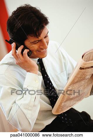 Businessman holding newspaper and cell phone, smiling View Large Photo Image Stock Photograph - Businessman holding newspaper and cell phone, smiling. Fotosearch