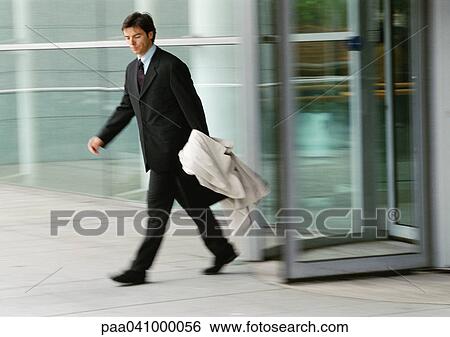Businessman leaving building, holding overcoat, blurred View Large Photo Image Stock Photograph - Businessman leaving building, holding overcoat, blurred. Fotosearch