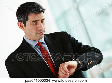 Businessman looking at watch, portrait View Large Photo Image Picture - Businessman looking at watch, portrait. Fotosearch