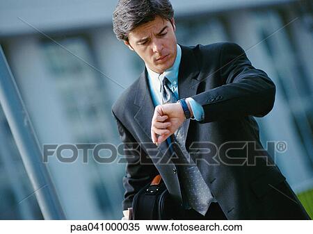 Businessman looking at watch, portrait View Large Photo Image Stock Photography - Businessman looking at watch, portrait. Fotosearch