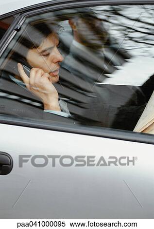 Businessman sitting in car, using cell phone, viewed through window View Large Photo Image Stock Photography - Businessman sitting in car, using cell phone, viewed through window. Fotosearch