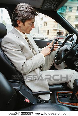 Businessman sitting in stationary car, using cell phone View Large Photo Image Stock Photo - Businessman sitting in stationary car, using cell phone. Fotosearch