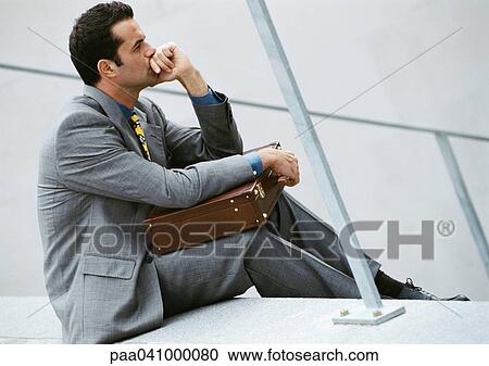 Businessman sitting on stairs, holding briefcase View Large Photo Image Stock Image - Businessman sitting on stairs, holding briefcase. Fotosearch