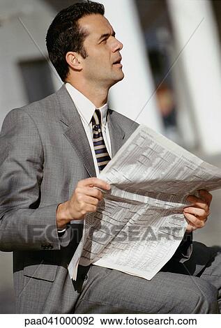 Businessman sitting outside, holding newspaper View Large Photo Image Stock Image - Businessman sitting outside, holding newspaper. Fotosearch