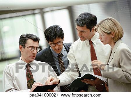Four business people examining document View Large Photo Image Stock Photo - Four business people examining document. Fotosearch
