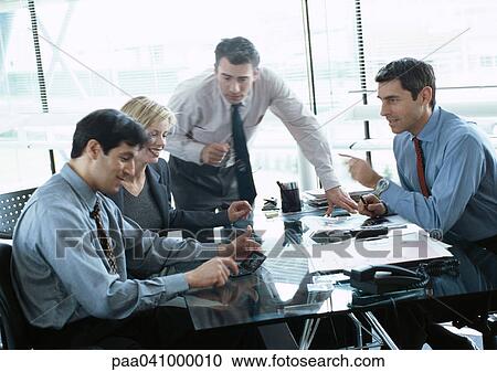 Stock Image - Four business people in conference room, blurred. Fotosearch