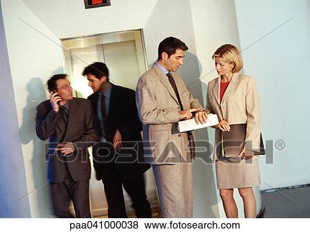 Four business people standing in front of elevator View Large Photo Image Stock Photo - Four business people standing in front of elevator. Fotosearch