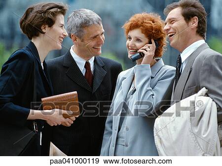 Four business people standing outside smiling, businesswoman on cell phone View Large Photo Image Stock Photo - Four business people standing outside smiling, businesswoman on cell phone. Fotosearch