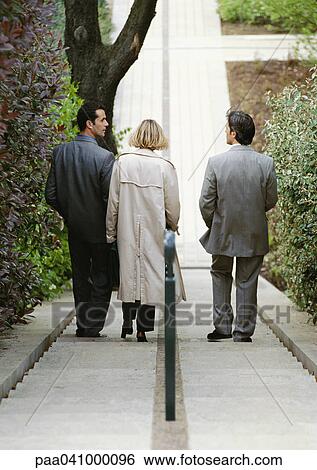 Three business people going down stairs, rear view View Large Photo Image Stock Photograph - Three business people going down stairs, rear view. Fotosearch