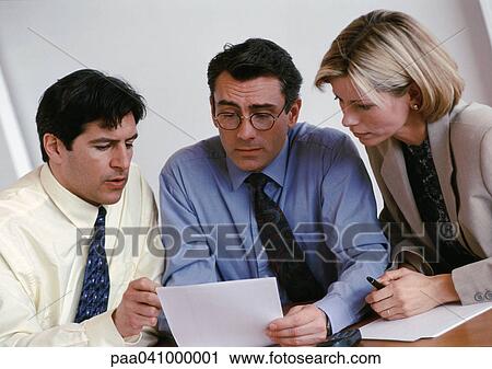Two businessmen and a businesswoman examining document View Large Photo Image Stock Image - Two businessmen and a businesswoman examining document. Fotosearch