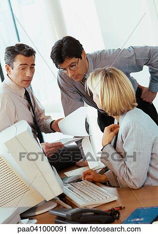 Two businessmen and a businesswoman examining documents View Large Photo Image Stock Image - Two businessmen and a businesswoman examining documents. Fotosearch