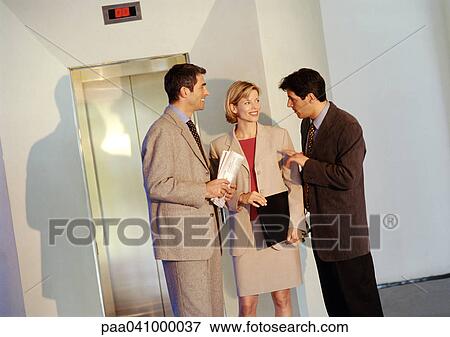 Two businessmen and a businesswoman standing in front of elevator View Large Photo Image Stock Photo - Two businessmen and a businesswoman standing in front of elevator. Fotosearch