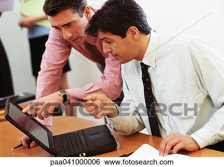 Stock Photograph - Two businessmen looking at laptop computer. Fotosearch