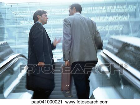 Two businessmen on escalators, low angle view View Large Photo Image Stock Image - Two businessmen on escalators, low angle view. Fotosearch