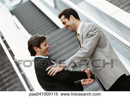Stock Photography - Two businessmen shaking hands in front of stairs. Fotosearch