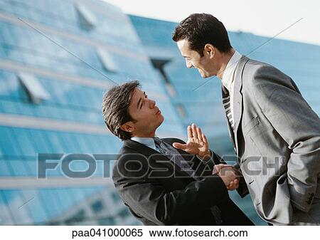 Two businessmen shaking hands outside, buildings in background View Large Photo Image Stock Photography - Two businessmen shaking hands outside, buildings in background. Fotosearch