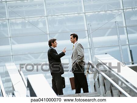 Two businessmen standing at the top of stairs View Large Photo Image Stock Image - Two businessmen standing at the top of stairs. Fotosearch