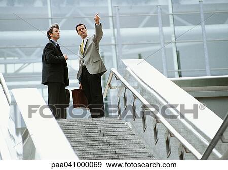 Two businessmen standing at the top of stairs View Large Photo Image Stock Photo - Two businessmen standing at the top of stairs. Fotosearch