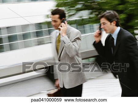 Two businessmen using cell phones outside, blurred View Large Photo Image Stock Photo - Two businessmen using cell phones outside, blurred. Fotosearch
