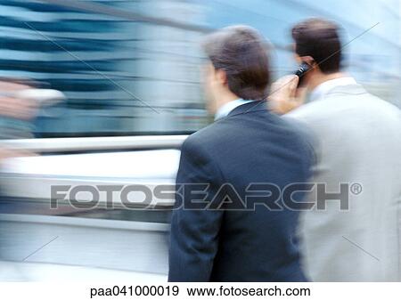 Two businessmen walking side by side, rear view, blurred View Large Photo Image Stock Photo - Two businessmen walking side by side, rear view, blurred. Fotosearch