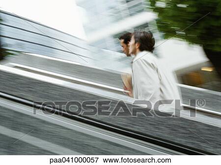 Stock Photo - Two businessmen walking up stairs outside, blurred. Fotosearch