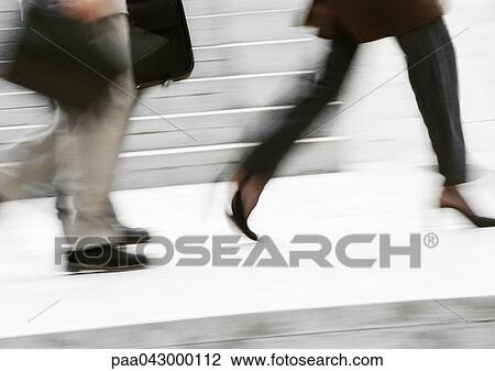 Stock Image - Business people running in street, low section, blurred. Fotosearch