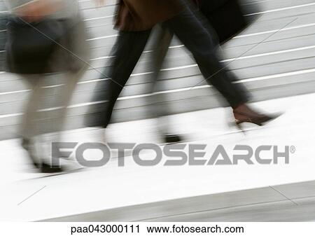 Stock Image - Business people walking in street, low section, blurred. Fotosearch