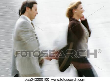 Stock Image - Business people walking, side view, blurred. Fotosearch