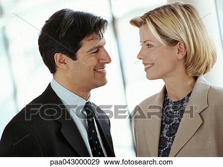 Stock Photo - Businessman and businesswoman face to face, smiling, close-up. Fotosearch