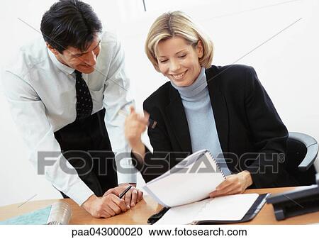 Stock Image - Businessman and businesswoman looking at document. Fotosearch