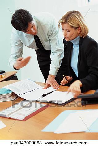 Businessman and businesswoman looking at documents on desk View Large Photo Image Stock Photo - Businessman and businesswoman looking at documents on desk. Fotosearch
