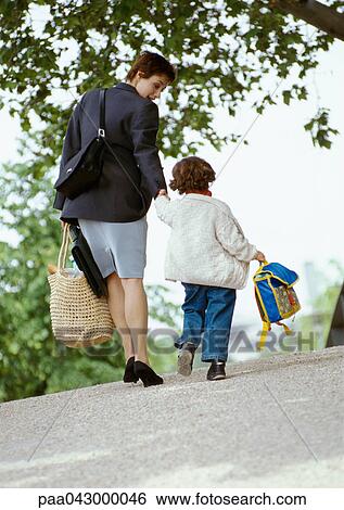 Stock Photograph - Businesswoman and child holding hands, walking, rear view. Fotosearch