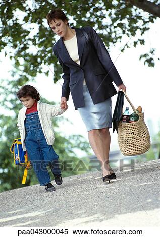 Stock Photography - Businesswoman and child holding hands, walking, full length. Fotosearch