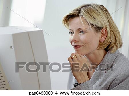 Businesswoman at computer screen, smiling View Large Photo Image Picture - Businesswoman at computer screen, smiling. Fotosearch