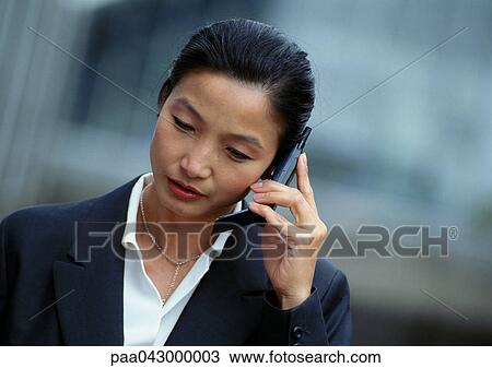 Businesswoman holding cell phone, looking down, portrait View Large Photo Image Stock Image - Businesswoman holding cell phone, looking down, portrait. Fotosearch