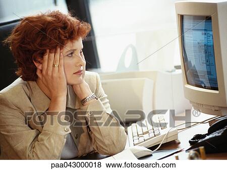 Businesswoman looking at computer screen, holding head View Large Photo Image Stock Photo - Businesswoman looking at computer screen, holding head. Fotosearch