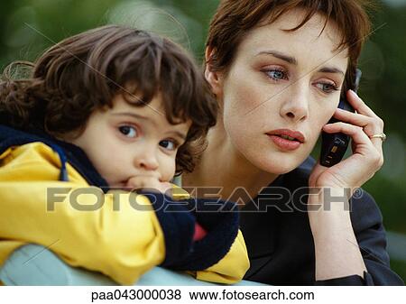 Businesswoman on cell phone next to child, close-up View Large Photo Image Stock Photo - Businesswoman on cell phone next to child, close-up. Fotosearch