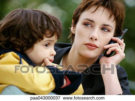 Businesswoman on cell phone with child, close-up View Large Photo Image Stock Photo - Businesswoman on cell phone with child, close-up. Fotosearch