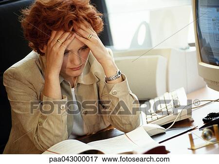 Businesswoman sitting at desk, hands on head View Large Photo Image Stock Photo - Businesswoman sitting at desk, hands on head. Fotosearch