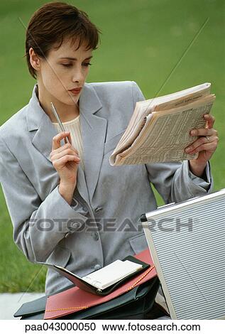Businesswoman sitting, looking at newspaper View Large Photo Image Stock Image - Businesswoman sitting, looking at newspaper. Fotosearch