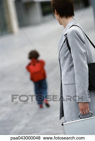 Businesswoman watching child walk away, rear view View Large Photo Image Stock Photo - Businesswoman watching child walk away, rear view. Fotosearch