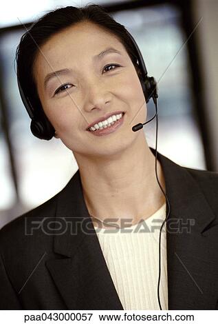 Stock Photo - Businesswoman wearing headset, smiling at camera, portrait. Fotosearch