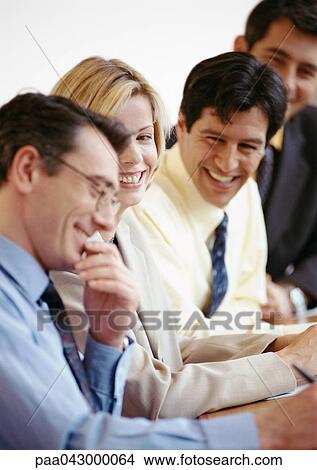 Four businesspeople sitting side by side, smiling View Large Photo Image Picture - Four businesspeople sitting side by side, smiling. Fotosearch